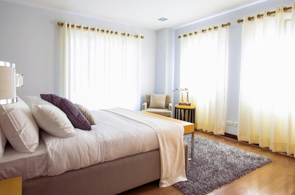 Bright modern bedroom with sunlight, cozy decor, and soft furnishings.